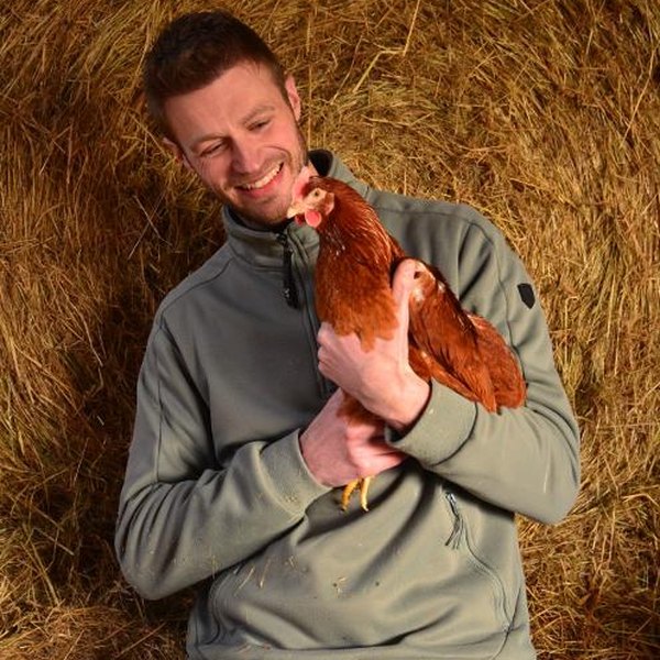 David Jolet, de la Ferme de Thimister, une de ses poules pondeuses dans les bras